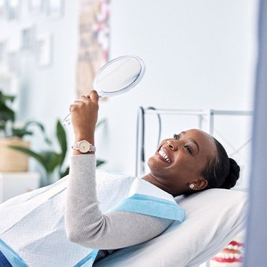 Woman smiling at reflection in handheld mirror