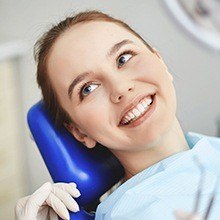 Woman in dental chair smiling during teeth cleaning visit