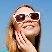 Smiling woman with a hand on her cheek after cosmetic dentistry