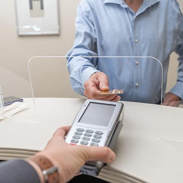 A man using a credit card to pay for his dental care