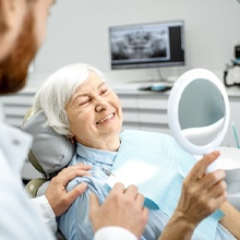Older woman in dental chair looking in mirror