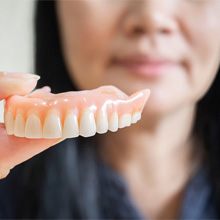 a person holding and caring for their dentures