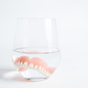 a denture in a glass cup of water