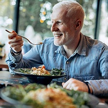 An older man eating a healthy meal at a restaurant