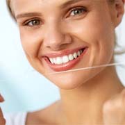 young woman smiling and holding up dental floss