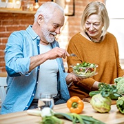 An older couple standing in the kitchen and preparing a healthy salad in West Palm Beach