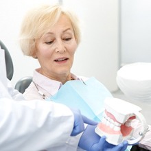 dentist showing a denture to a patient