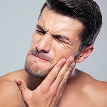 Man in pain holding cheek before gum disease treatment