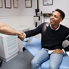 man in dental chair shaking his dentist’s hand 
