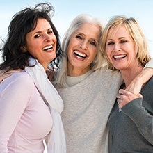 Three older women with complete and partial dentures laughing together