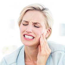 Woman in pain holding her cheek before root canal therapy
