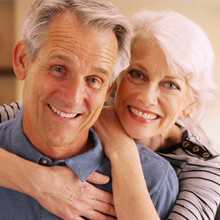 Older couple smiling after smile makeovers