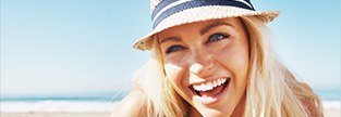 Young woman at beach laughing after Invisalign treatment