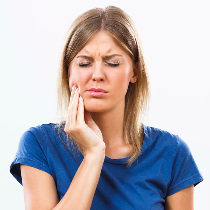 Woman holding jaw in pain before T M J therapy for jaw pain