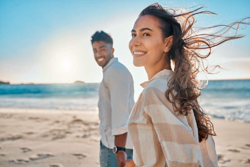 A couple on the beach smiling with their new cosmetic dentistry procedures